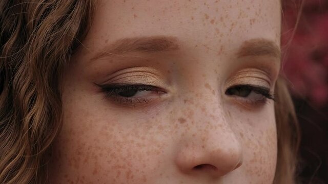 Close-up portrait of a little girl's face with red hair and freckles.
