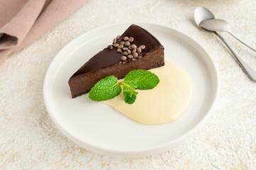 Chocolate cheesecake with butter cream. Decorated with mint. On a flat white plate. Light background. View from above.