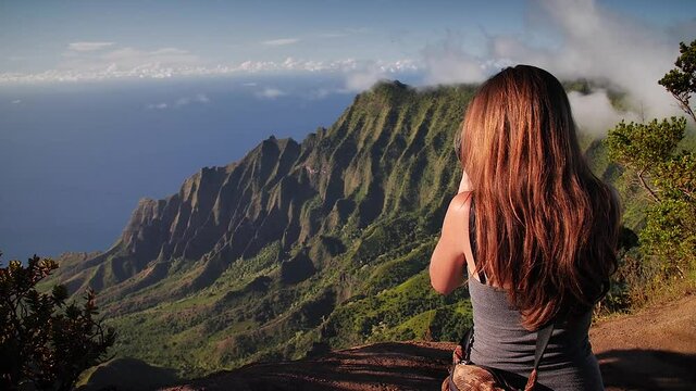 Woman overlooking dramatic Na Pali Coast at sunset in Kauai, Hawaii. Mid angle, parallax movement, HD.