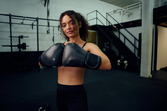 African American female boxer training at the gym with boxing gloves on. Mixed race female holding boxing gloves in air. High quality photo