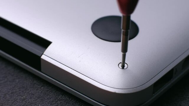 Macro footage - master screwing small screw with screwdriver tool, disassembling and repairing of broken laptop.