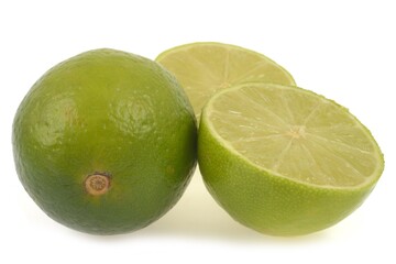 Citrons verts dont un coupé en deux en gros plan sur fond blanc