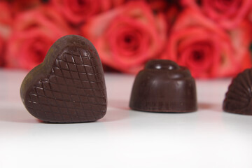 Obraz na płótnie Canvas Chocolate Candy With Roses in Background, Shallow DOF Focus on Chocolate