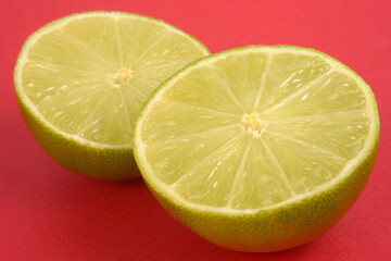 Citron vert coupé en deux en gros plan sur fond rouge