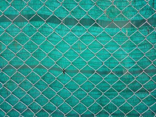 Background of steel mesh with green plastic sheet.