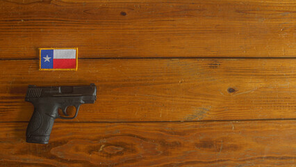 Black snub nosed revolver below a Texas state flag patch on a wooden plank background