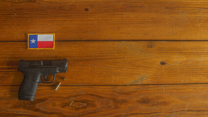 semi-automatic handgun, with ammunition, below a Texas state flag patch on a textured wooden plank background