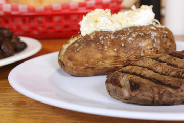 Sirloin Steak With Baked Potato and fresh rolls in background Shallow DOF Focus on Steak