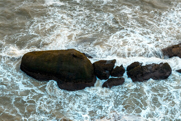 Top view of foamy waves hitting rocks