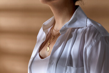 beauty, fashion and jewelry trends concept - close up of woman in white shirt wearing golden multi...