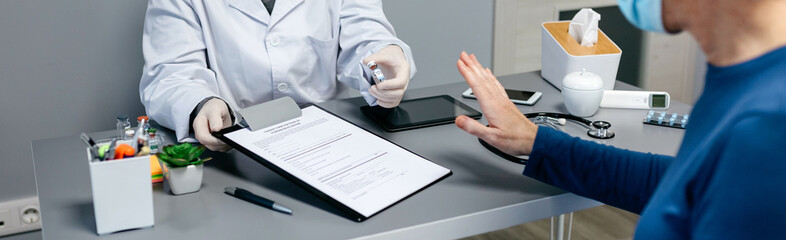 Female patient refusing the coronavirus vaccine offered by her doctor