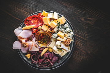 plate with bacon, cheese cubes, meat, salami, ham on wooden table background