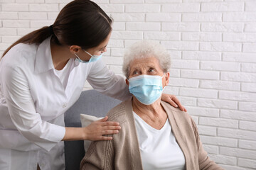 Doctor taking care of senior woman in protective mask at nursing home