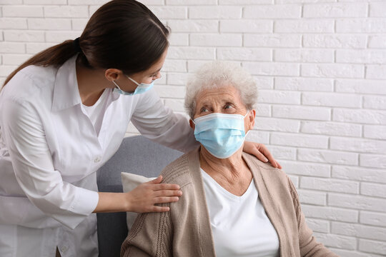 Doctor Taking Care Of Senior Woman In Protective Mask At Nursing Home