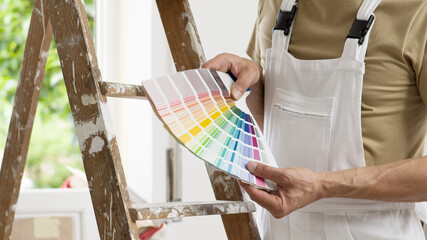 hands of house painter man decorator choose the color using the sample swatch, work of the house to...