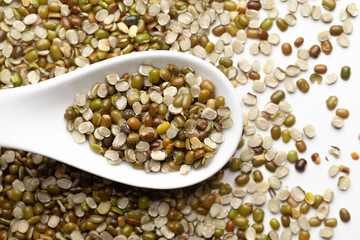 Macro Close-up of Organic split green urad dal (Vigna mungo) on a white ceramic soup spoon. Top view,  over gradient background of itself.