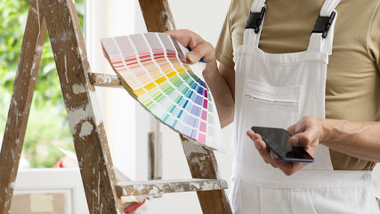 hands of house painter man decorator choose the color using the sample swatch, work of the house to...