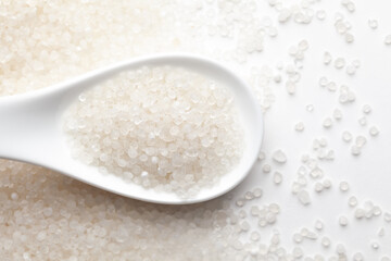 Macro Close up of organic white sago or sabudana small size on a white ceramic soup spoon. Top view,  over gradient background of itself.