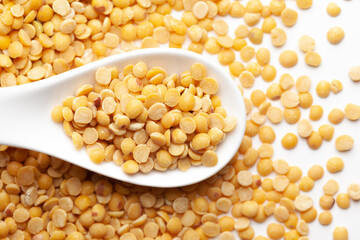 Macro Close-up of Organic arhar dal (Cajanus cajan) on a white ceramic soup spoon. Top view, over gradient background of itself.