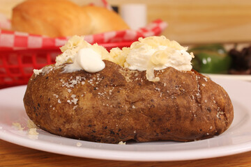 Sirloin Steak With Baked Potato and fresh rolls in background Shallow DOF