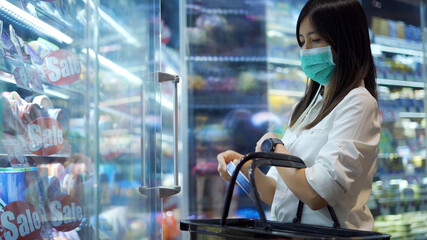 Fototapeta premium Woman in protective medical mask is choosing to buy items at supermarket.