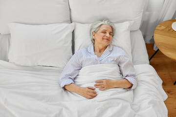 old age and people concept - happy senior woman sleeping in bed at home bedroom