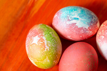 Multi-colored eggs on the table for Easter. Brown background.
