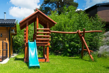 Fototapeta na wymiar Wooden house and a slide for children in the garden