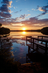 Scenic and beautiful sunset and cloudy sky and their reflections on a calm lake and jetty in...