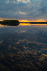 Scenic and beautiful sunset and dramatic cloudy sky and their reflections on a calm lake in Finland at summer.