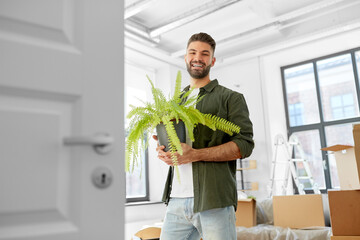 moving, people and real estate concept - happy smiling man with fern flower at new home