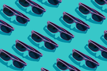 Purple sunglasses lay down on a pastel blue background. Flat lay pattern composition, summer chill...