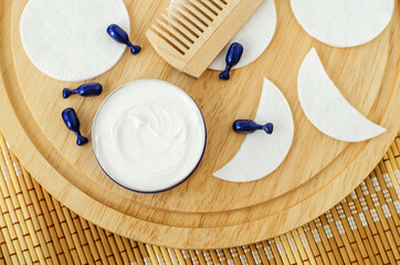 White facial mask (face cream, shea butter, body butter) in a small jar, cosmetic serum capsules,...