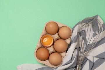 Whisk or egg beater with brown chicken eggs in eco basket. Fresh egg on morning breakfast, flat lay, copy space.