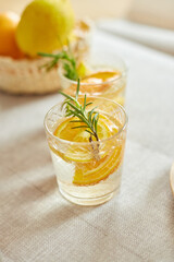 Citrus and rosemary fresh lemonade in glass on a white table at home