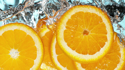 Fresh oranges slices dropped into water with splash