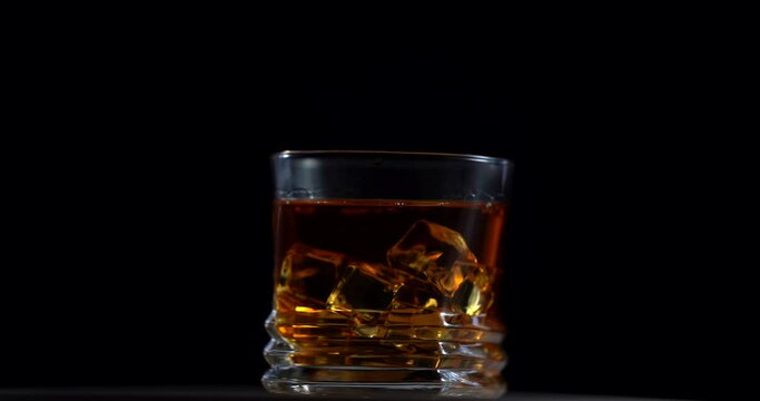 Super Slow Motion Shot of Pouring Whiskey into Glass at 100fps with Camera Movement. Rotation glass