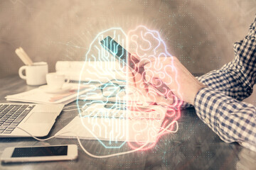 Double exposure of man's hand holding and using a digital device and brain hologram drawing. Data concept.