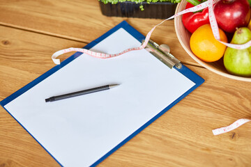Top view of Nutritionist, dietitian workplace with measuring tape and bowl with healthy vegetables...