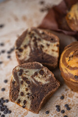 Soft and moist chocolate banana muffins with dark chocolate drops on grey rustic table. Homemade baked twisted cupcakes. Natural light, selective focus, copy space
