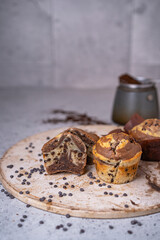 Soft and moist chocolate banana muffins with dark chocolate drops on grey rustic table. Homemade baked twisted cupcakes. Natural light, selective focus, copy space