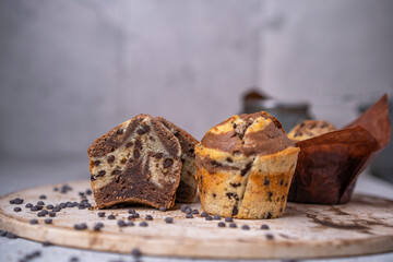 Soft and moist chocolate banana muffins with dark chocolate drops on grey rustic table. Homemade baked twisted cupcakes. Natural light, selective focus, copy space