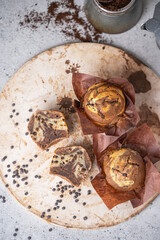 Soft and moist chocolate banana muffins with dark chocolate drops on grey rustic table. Homemade baked twisted cupcakes. Natural light, selective focus, copy space