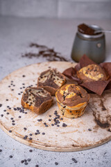 Soft and moist chocolate banana muffins with dark chocolate drops on grey rustic table. Homemade baked twisted cupcakes. Natural light, selective focus, copy space