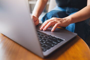 Closeup image of a woman working and typing on laptop computer keyboard on the table