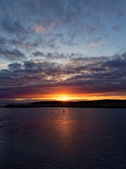 A Winter Sunset over the isle of Bressay and Bressay Sound, with the orange evening light being reflected in the calm water.