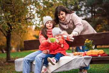 Caring woman try hot drink from stainless thermos before give it to little preteen boy. Happy cozy...