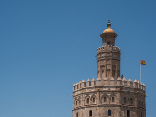 View of Torre del Oro (Tower of Gold) with spanish flag and blue sky and copy space
