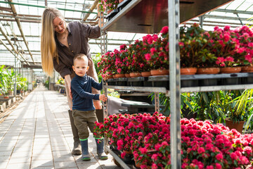 Woman greenhouse worker and her son pulling a cart with flowers