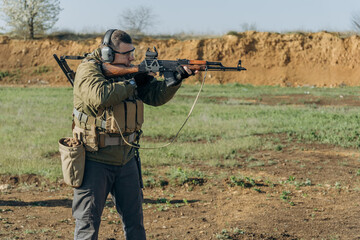 White man in military uniform shoots an AK at a shooting range